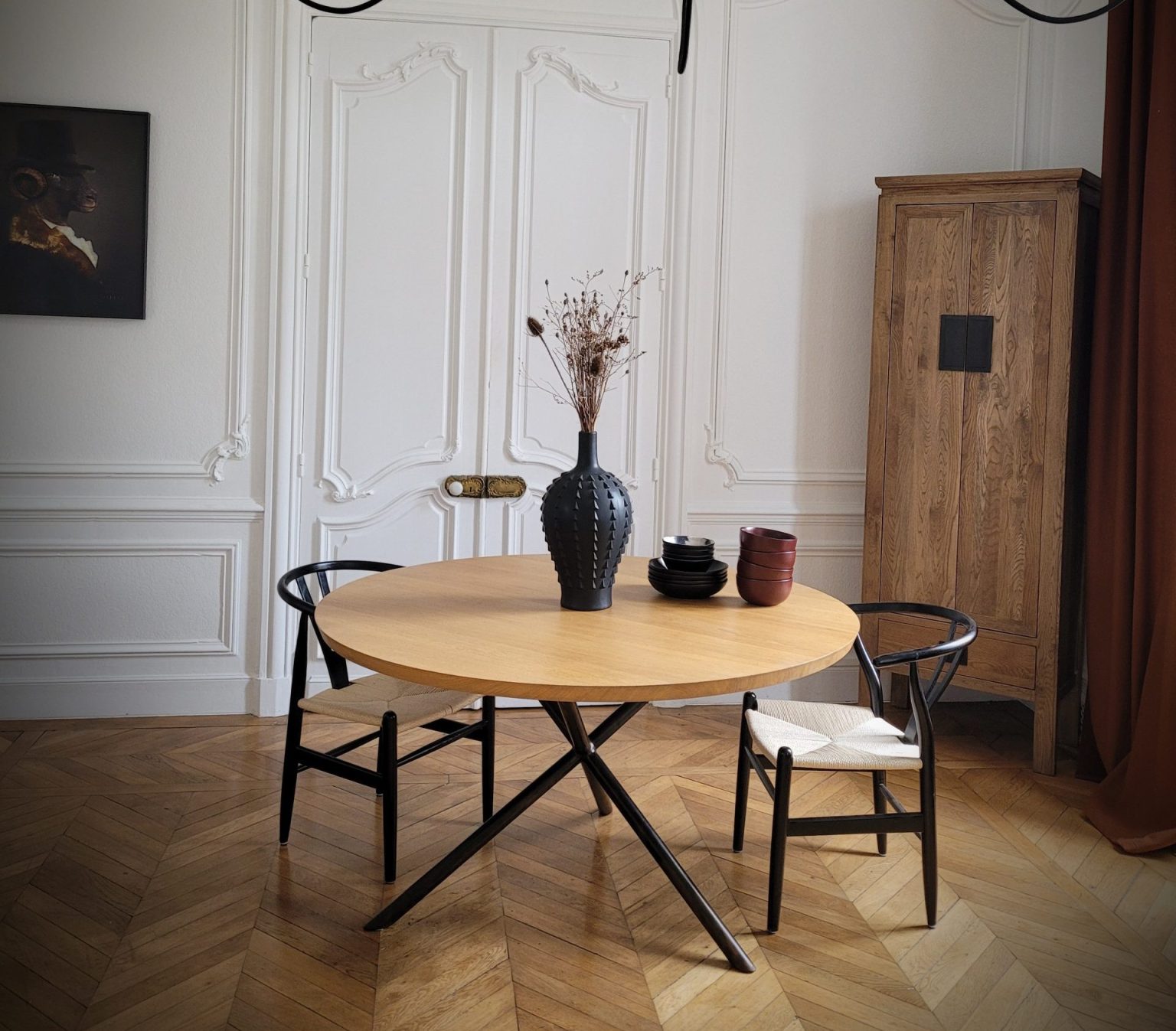 Table à manger artisanlae ronde en bois massif et acier dans un interieur haussmanien